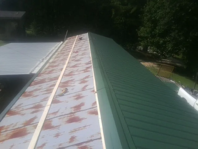 Old rusted panels beside newly installed green metal roofing — Wind Damage Roof Repair by Roofing Brothers in Carlsbad