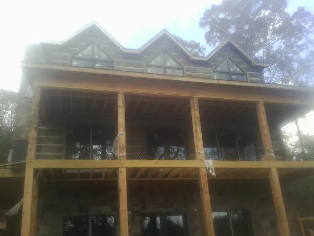 Dormers and porch framing on a large log home under construction — Roof Coating work by our crew in Carlsbad