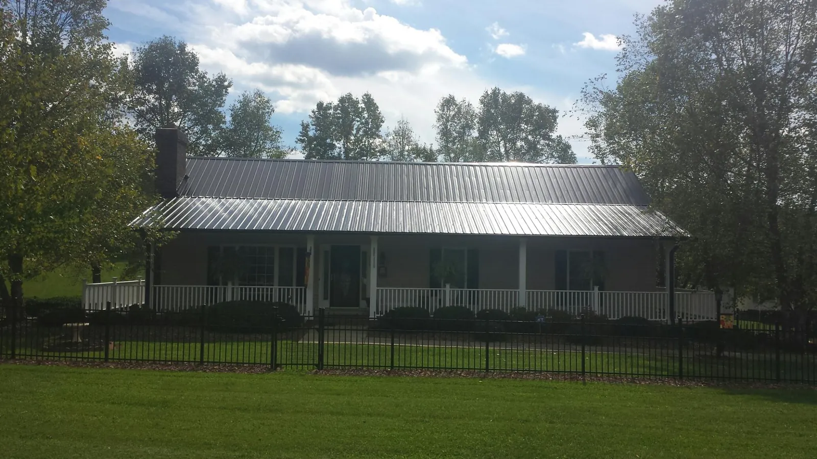 Gray metal roof on a brick ranch with a full width front porch — Gutter Guard Installation work by our crew in Carlsbad