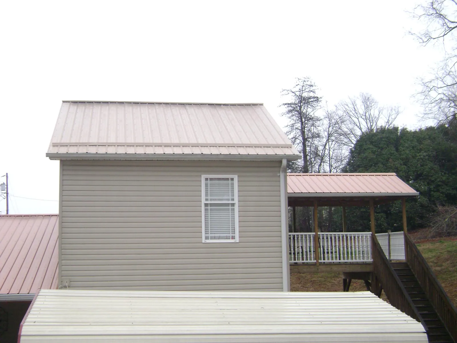 Tan metal roofs on a two story addition and attached porch, from a Roof Replacement job in Carlsbad