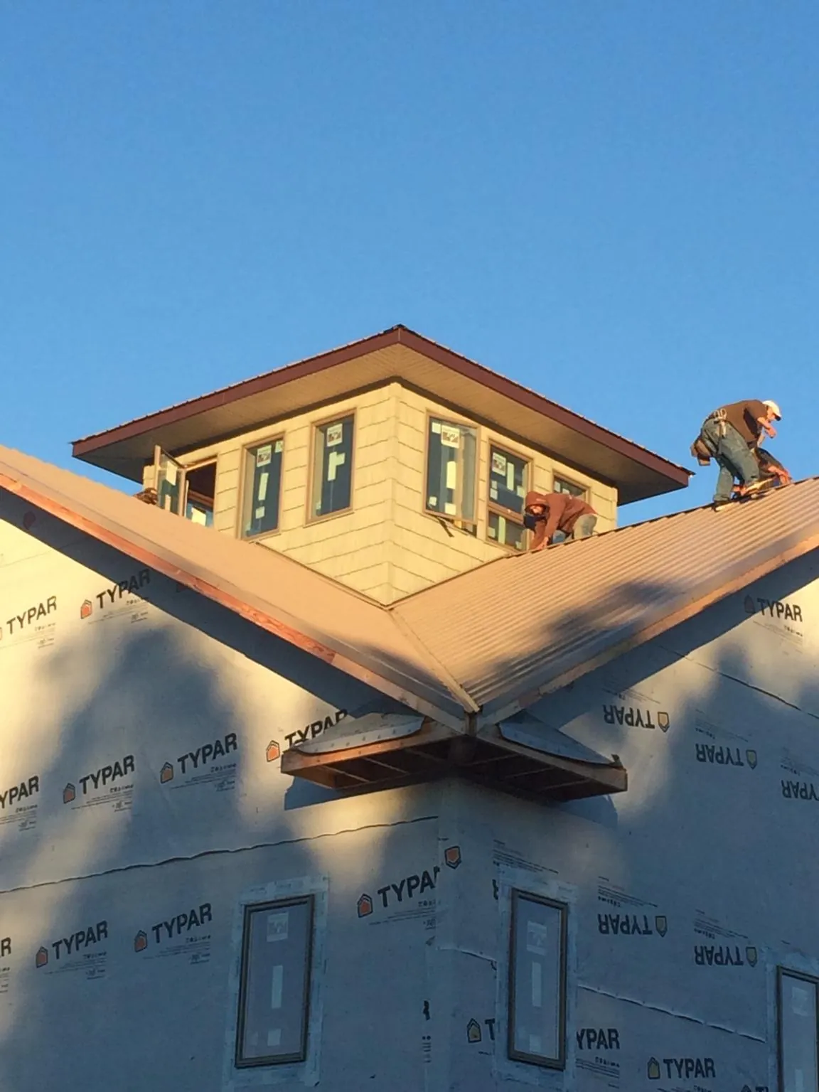 Roofers working around a rooftop cupola on a new metal roof at sunset — Roof Waterproofing in Carlsbad by Roofing Brothers